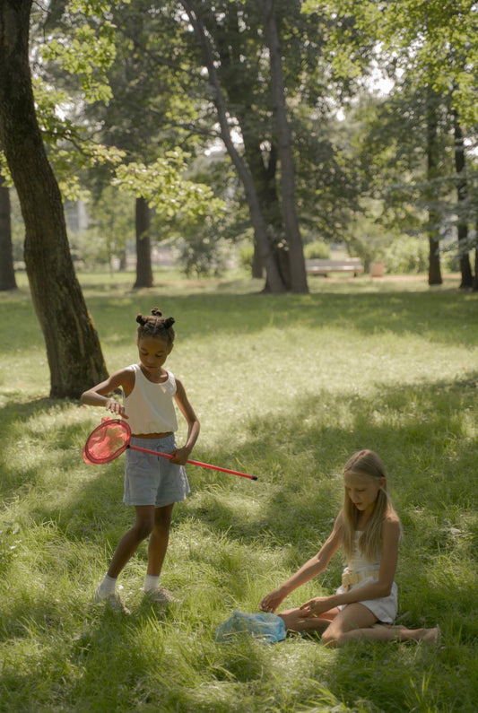 Meisje met een schepnetje speelt buiten in het gras