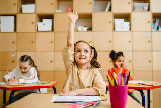 Kinderen in een klaslokaal, een meisje steekt haar vinger op